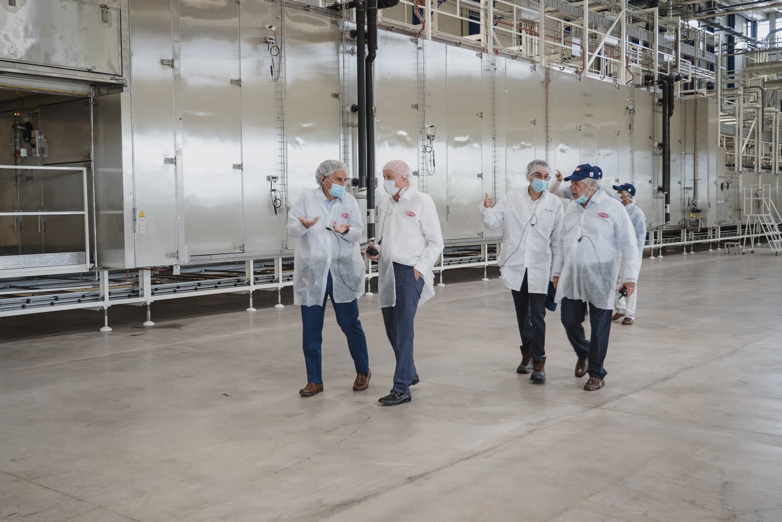 Recorrido por una línea de producción durante la inauguración, con personal de planta a media distancia.