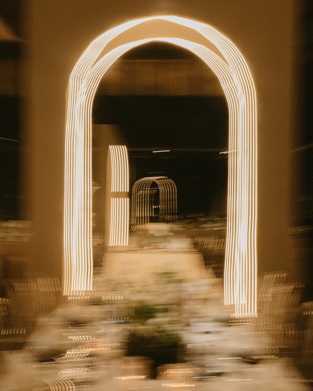 An illuminated arch glowing in the dark, opening onto a second arch further along.