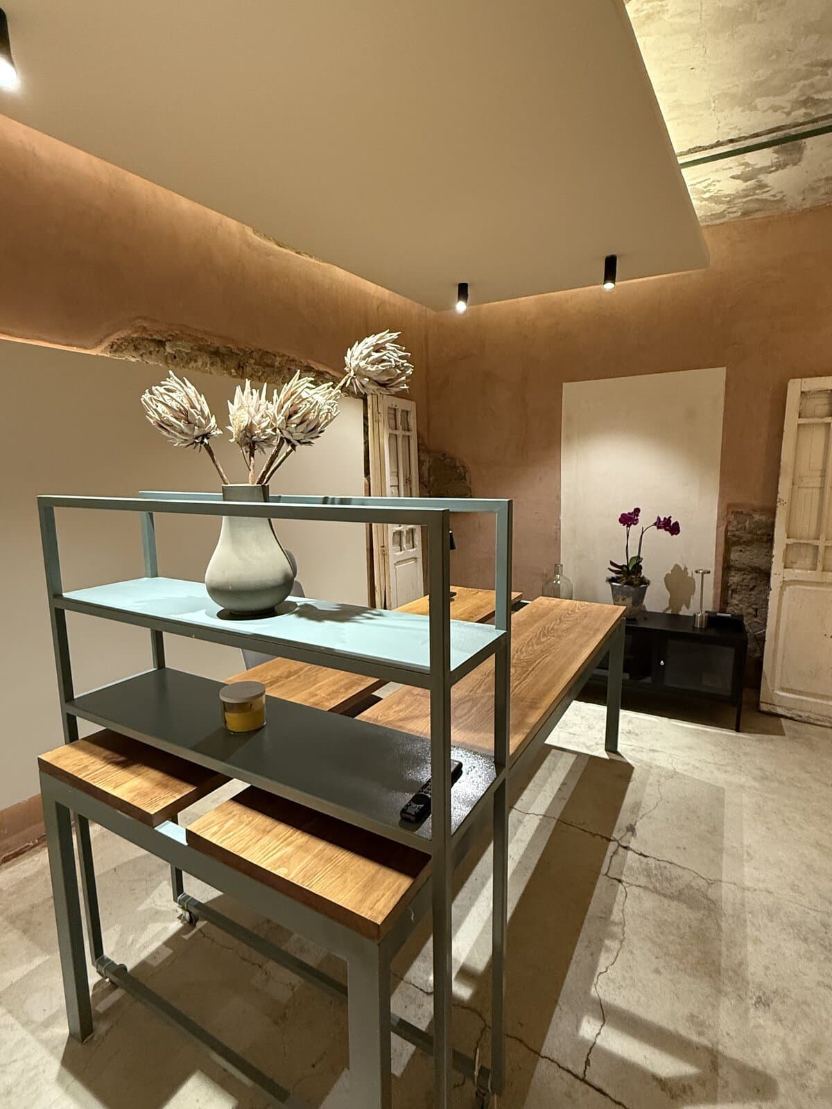 Oficina de CMeraz Studio en Melchor, con muros de terracota, mesa de madera y flores secas.