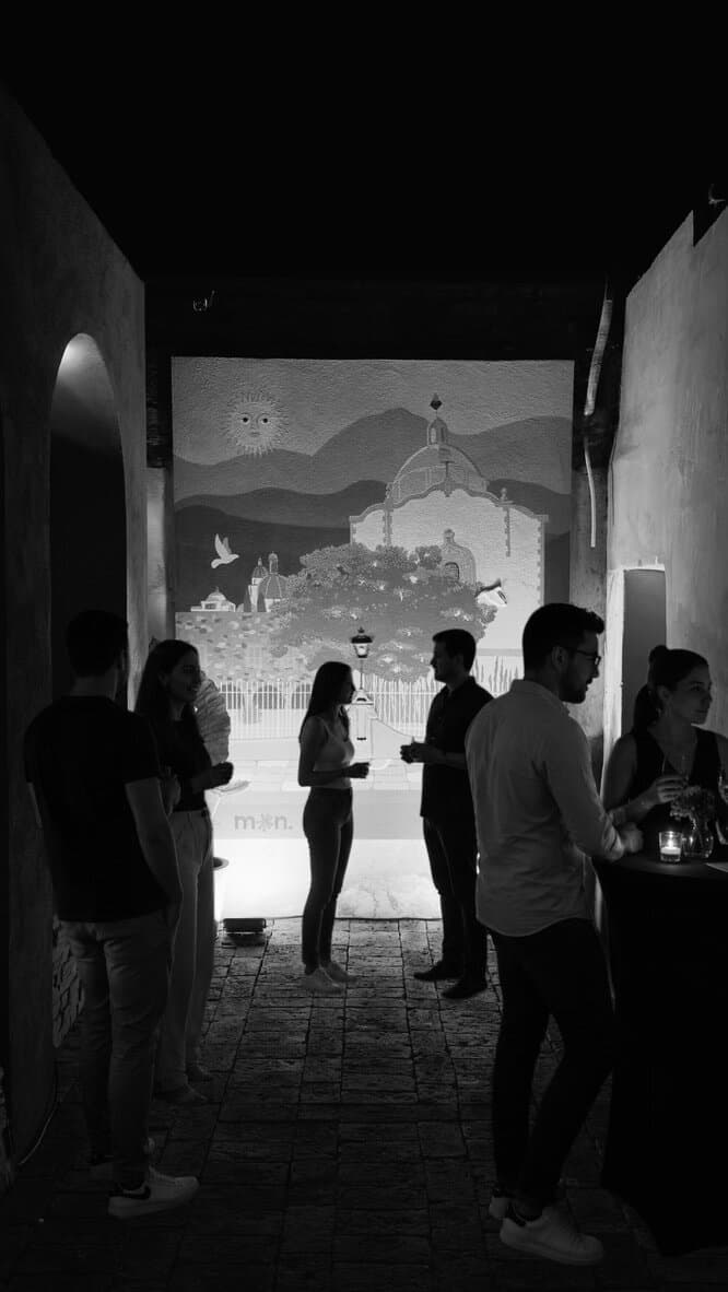 Grupo de personas conversando de noche en el patio interior de Melchor, en blanco y negro.