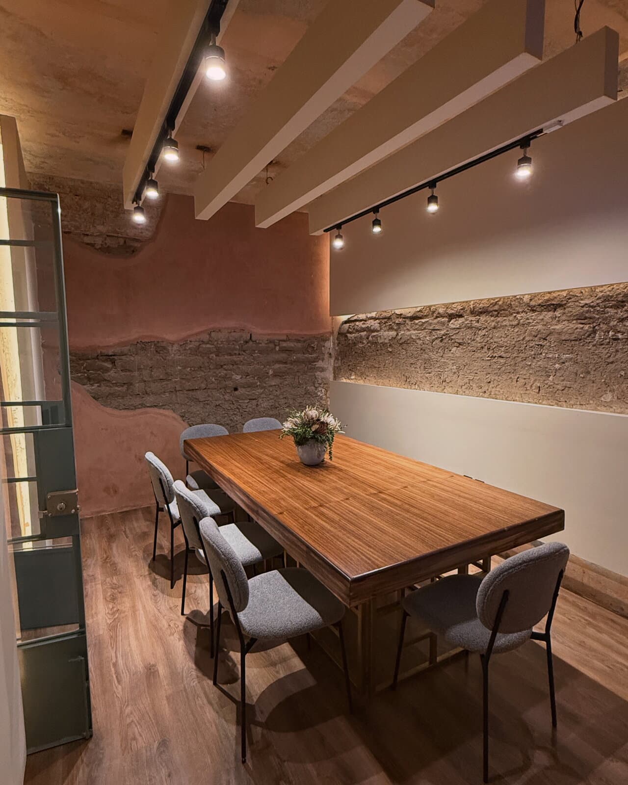 Sala de juntas de Melchor con mesa de piedra, sillas tapizadas y una puerta de vidrio hacia el patio.
