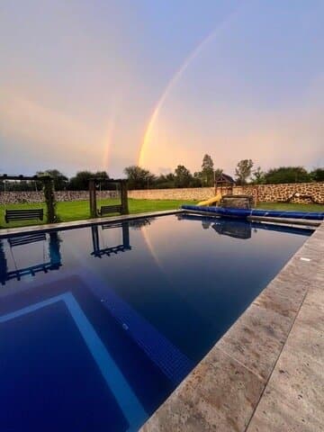Arcoíris sobre la alberca de Villa Alvento al atardecer.